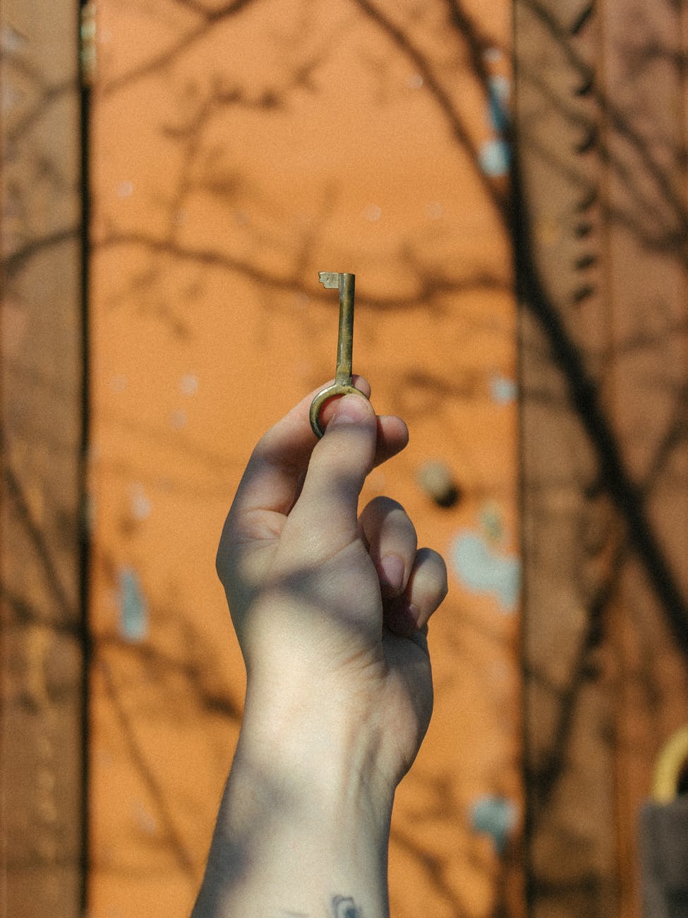hand holding antique key against rustic door